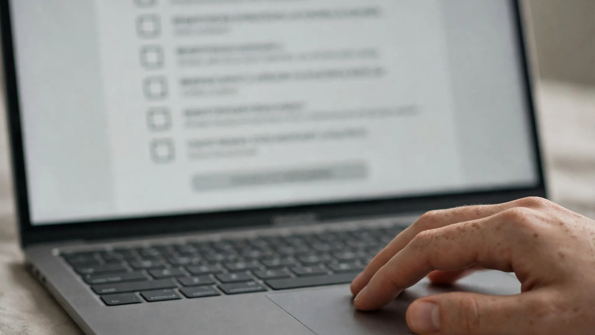 Close-up of a laptop screen showing a webinar registration form with checkboxes and a hand on the trackpad